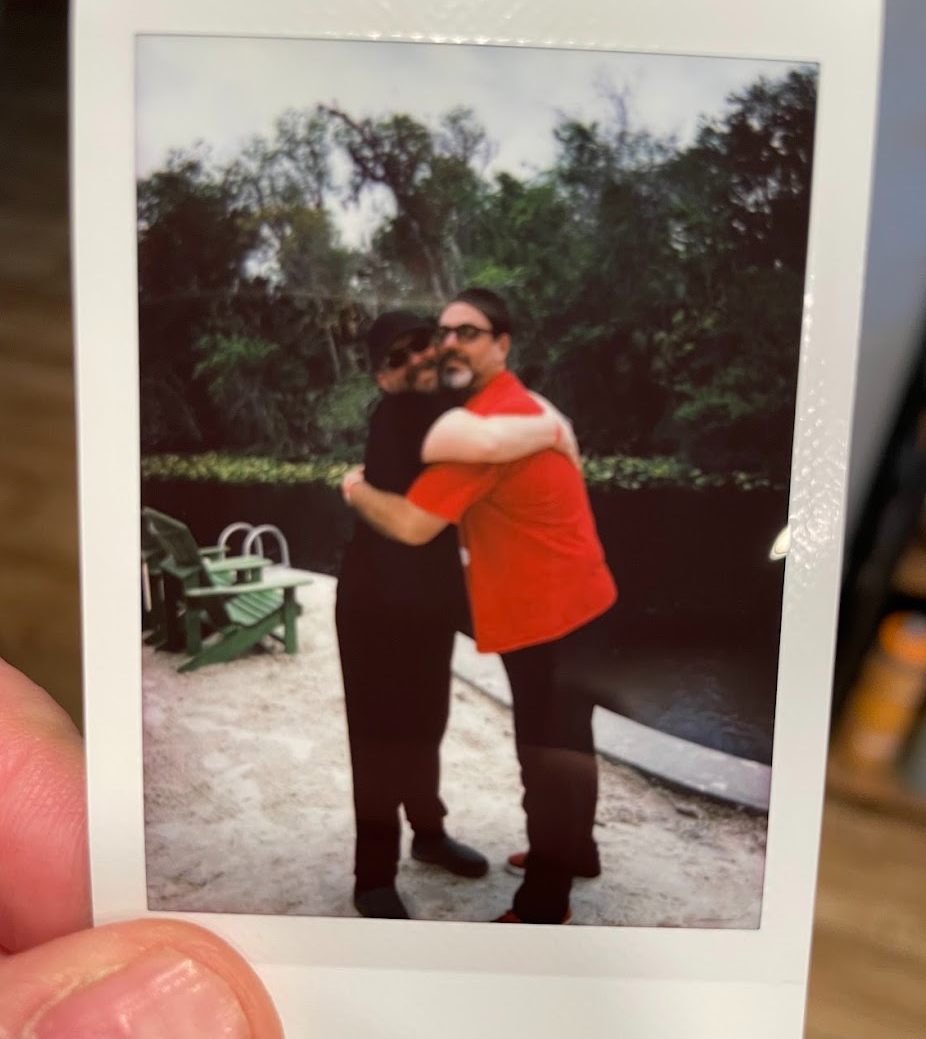 I way-too-small polaroid of two grown men hugging. 